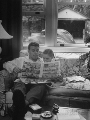 nina-leen-father-sitting-on-couch-with-pigtailled-daughter-reading-to-her-the-sunday-comic-pages