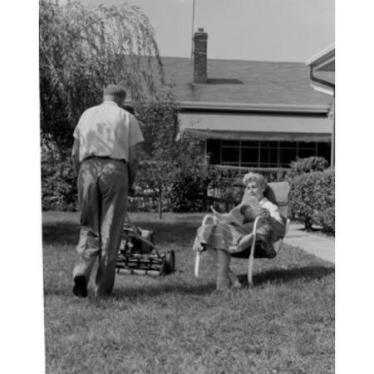 man-mowing-lawn-and-woman-reading-newspaper-in-garden-poster-print-18-x-24_969716