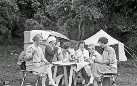 groupofsixwomenhavingbreakfastatatablewhilecamping-thereisaboxofweetbixonthetableandsomeofthewomenareeatingeggs-ngairehooperisseatedfrontleftandphotographerthelmar