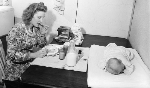 vintage-woman-eating-breakfast-with-baby-on-table